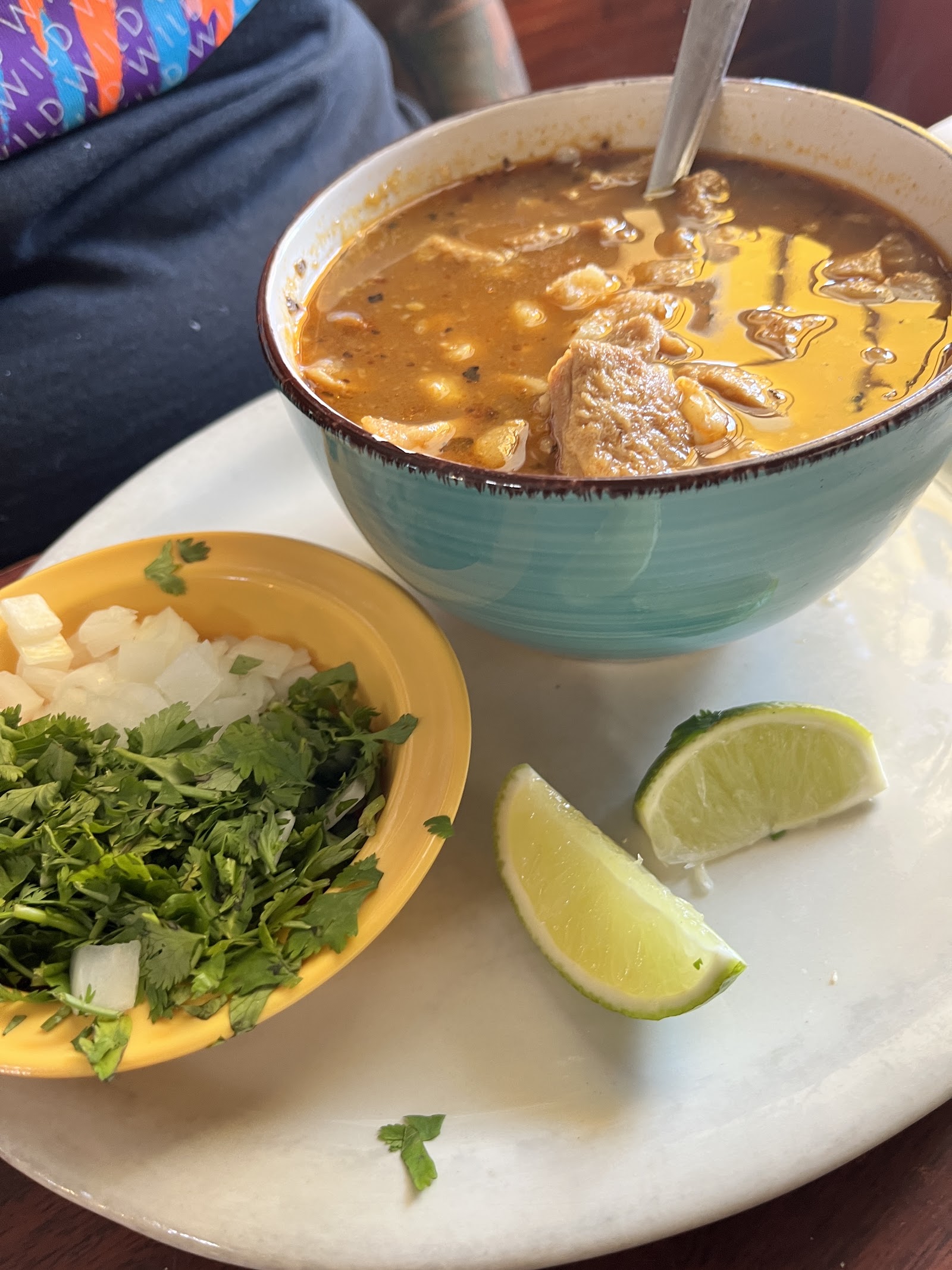 Bowl of menudo served with fresh cilantro, onion, and lime