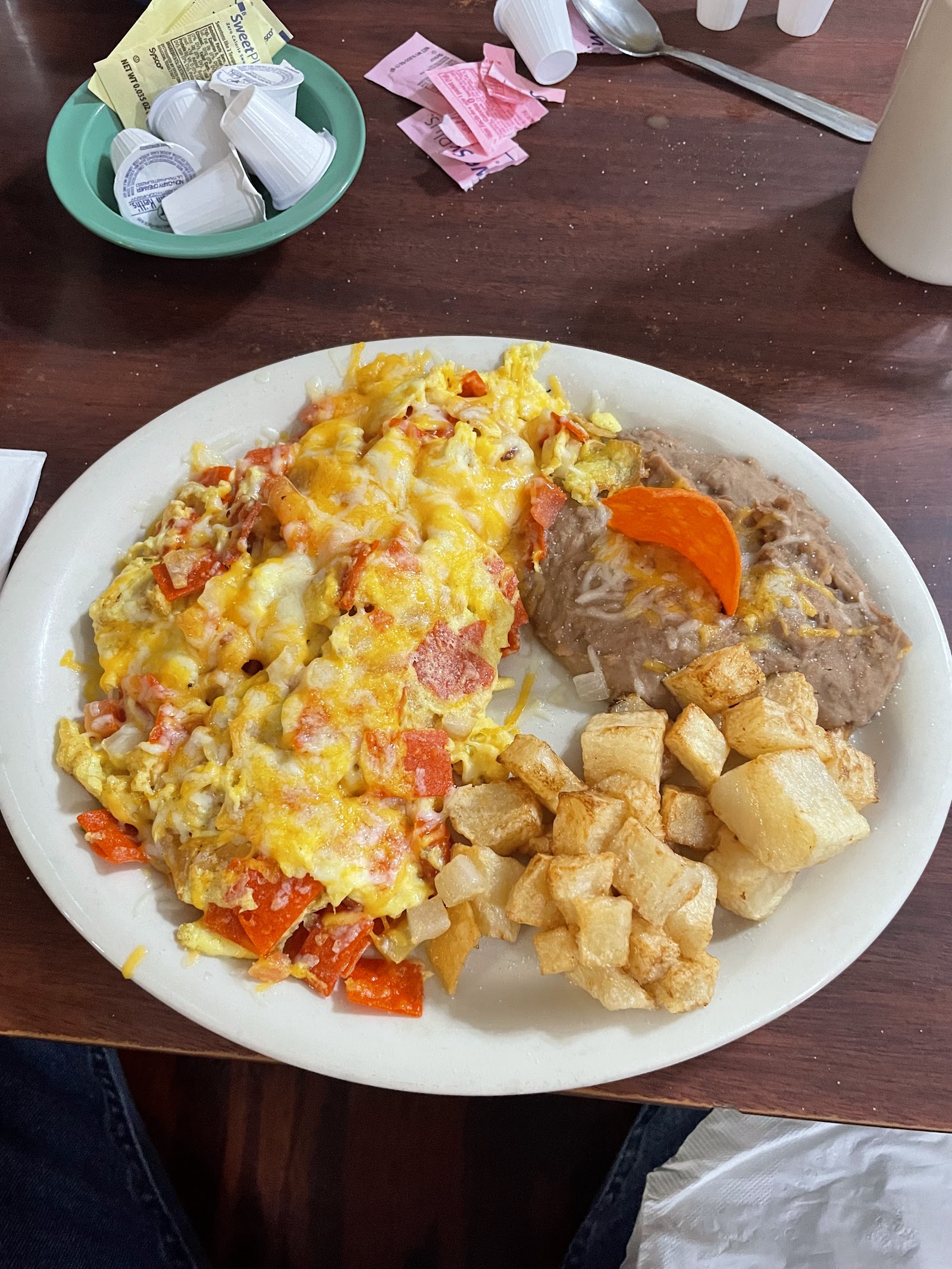 Breakfast plate with scrambled eggs, tomato, papas, and refried beans