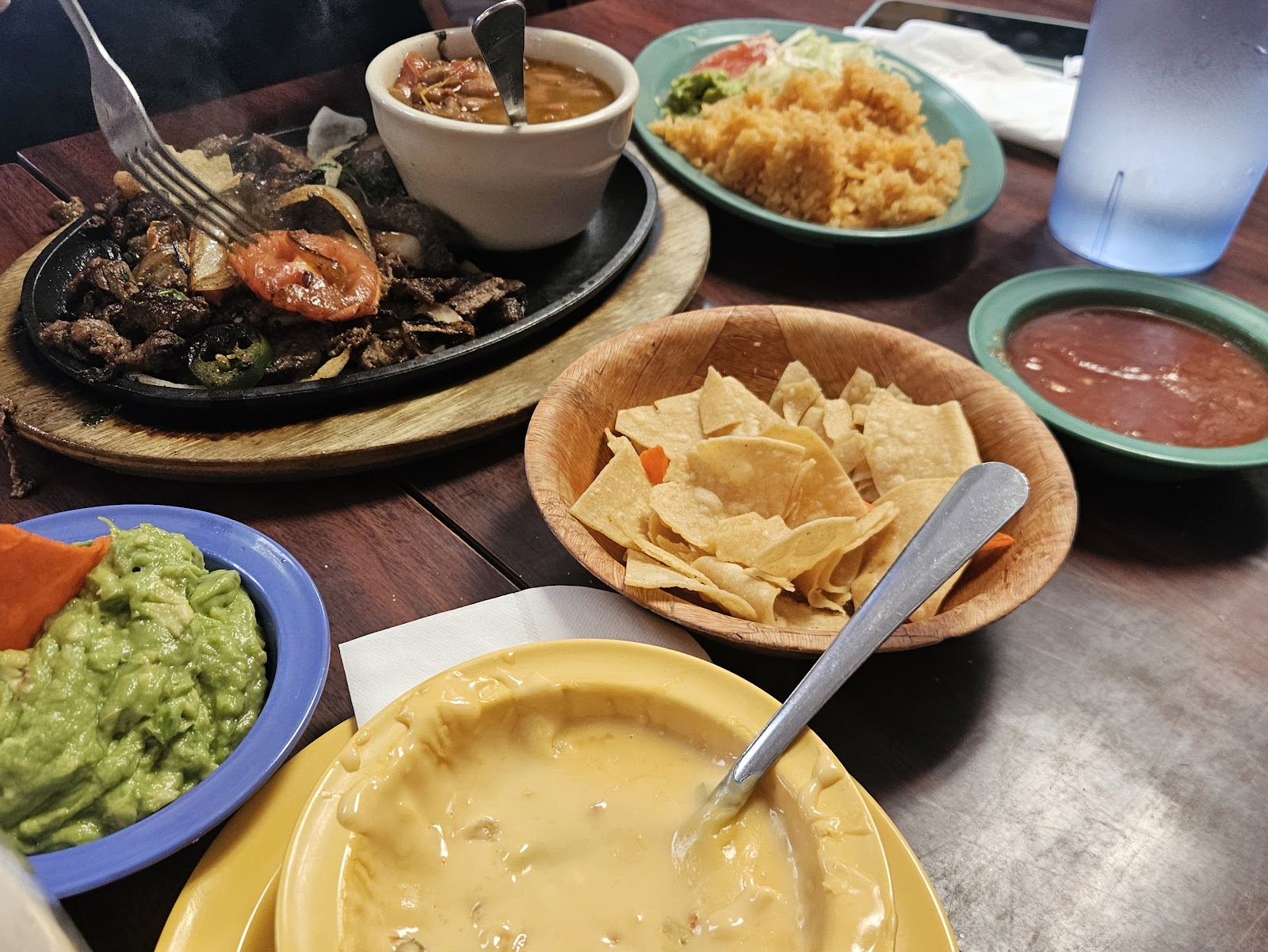 Sizzling fajita platter with queso, guacamole, rice, and chips at El Sabrosito